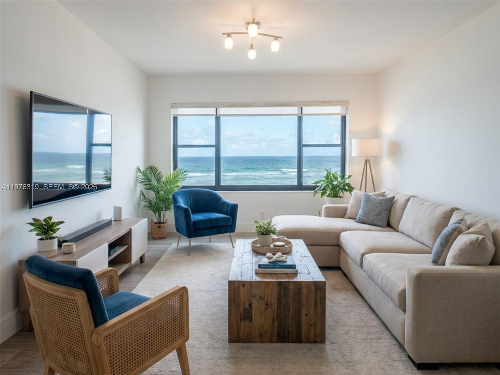 A living room features a beige sectional, two blue chairs, and a view of the ocean — 3300 N Surf Rd # 26A, Hollywood FL 33019, HOLLYWOOD, FL
