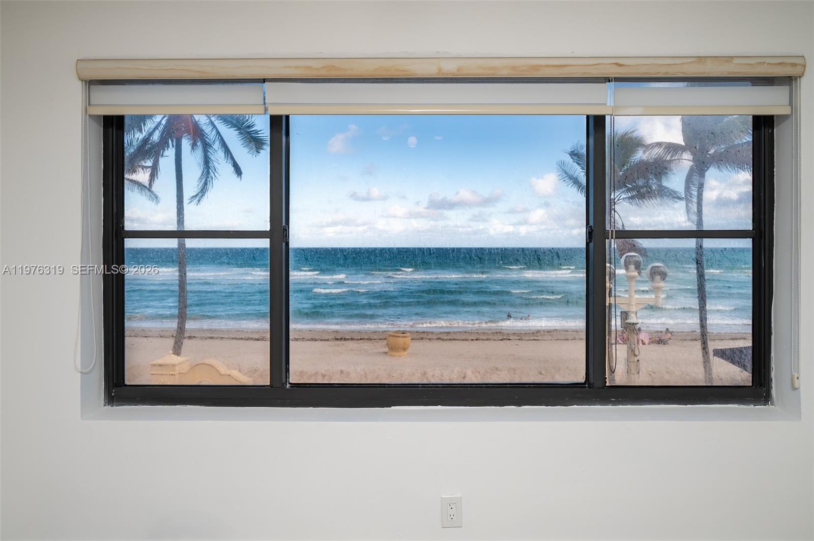 A large window with black frames offers a direct view of the ocean and beach — 3300 N Surf Rd # 26A, Hollywood FL 33019, HOLLYWOOD, FL