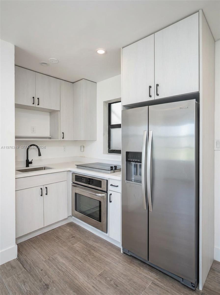 A small kitchen features light wood-grain cabinets, stainless steel appliances, and a black faucet — 3300 N Surf Rd # 26A, Hollywood FL 33019, HOLLYWOOD, FL