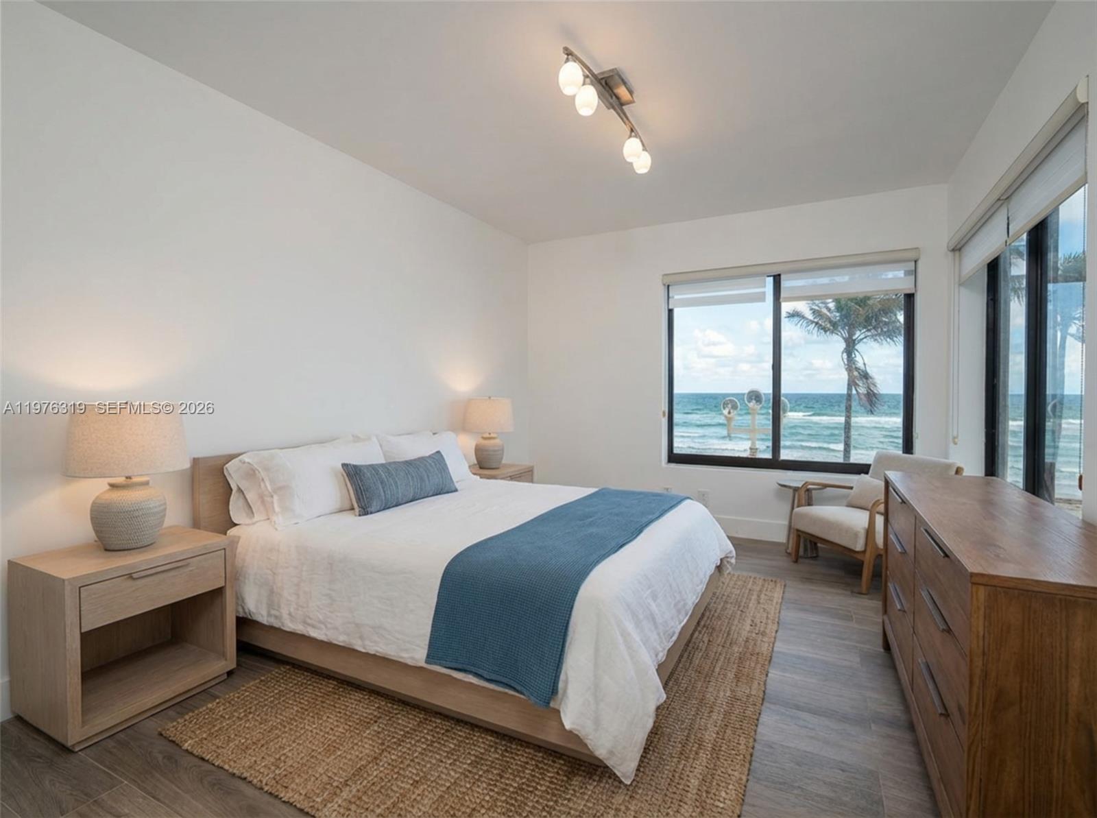A bedroom features a bed with a blue runner, light wood furniture, and ocean views — 3300 N Surf Rd # 26A, Hollywood FL 33019, HOLLYWOOD, FL