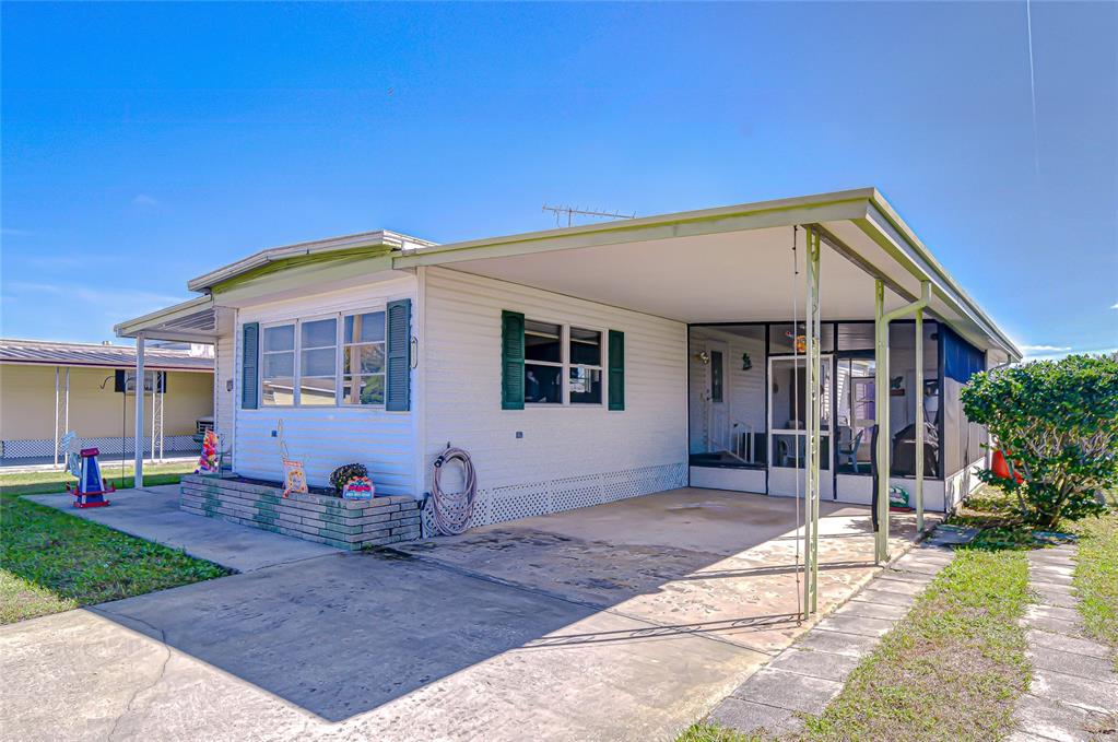 A single-story manufactured home with a carport, screened-in porch, and white siding — 35132 ZEPHYR SHORES DRIVE, ZEPHYRHILLS, FL