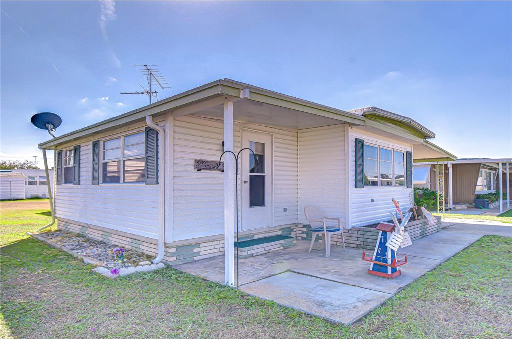 A single-story mobile home with white siding, a covered porch, and a concrete patio area — 35132 ZEPHYR SHORES DRIVE, ZEPHYRHILLS, FL