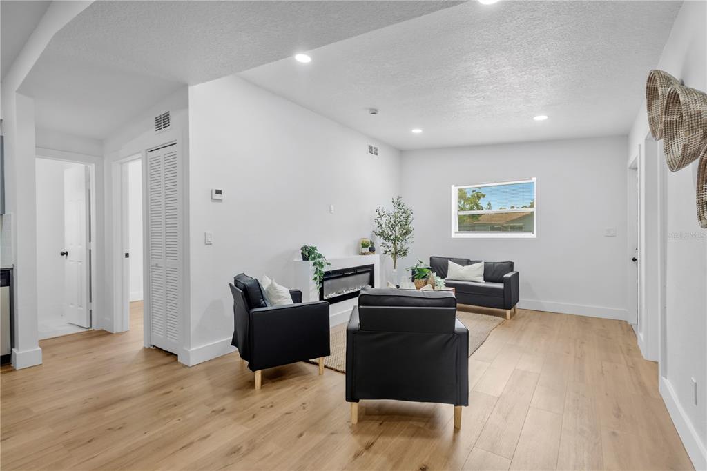 A living room features light wood flooring, white walls, a fireplace, and black furniture — 4628 15TH AVENUE S, ST PETERSBURG, FL