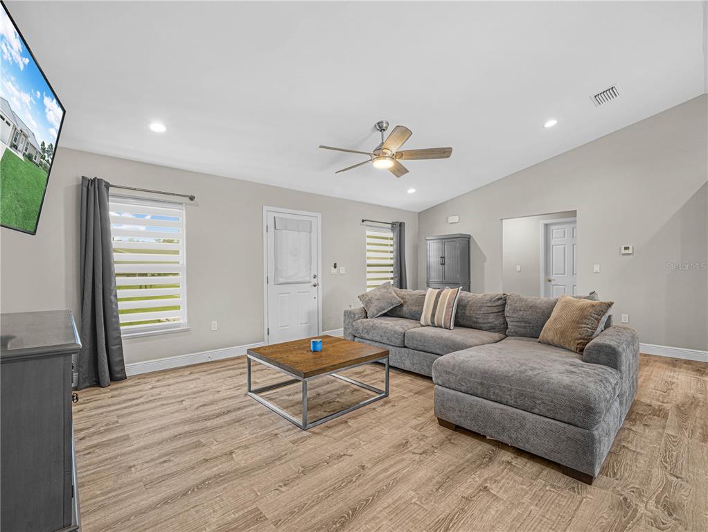 A living room features a gray sectional sofa, wood-look flooring, and a ceiling fan — 270 LINCOLN ROAD NE, LAKE PLACID, FL