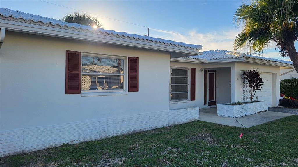 A single-story white house with a tiled roof, red shutters, and a front lawn — 14140 88TH AVENUE, SEMINOLE, FL