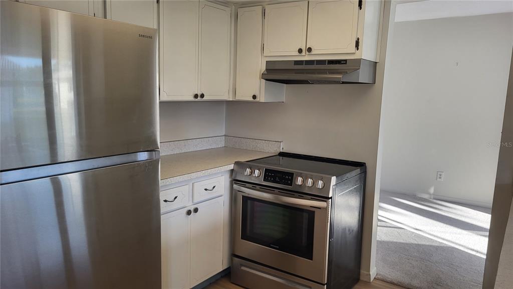 A kitchen features white cabinets, stainless steel appliances, and light-colored countertops — 14140 88TH AVENUE, SEMINOLE, FL
