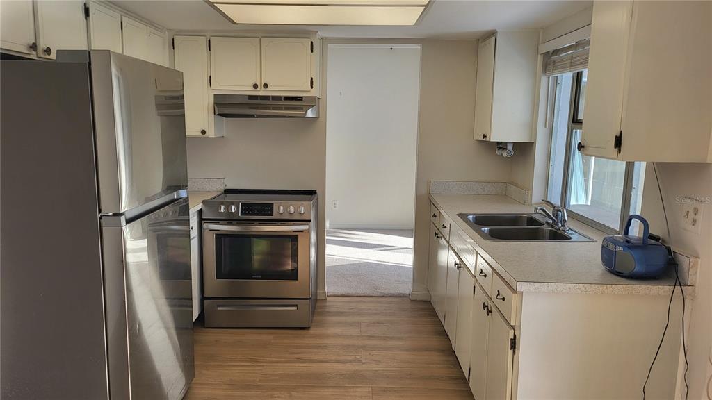 A kitchen with white cabinets, stainless steel appliances, and light wood-look flooring — 14140 88TH AVENUE, SEMINOLE, FL