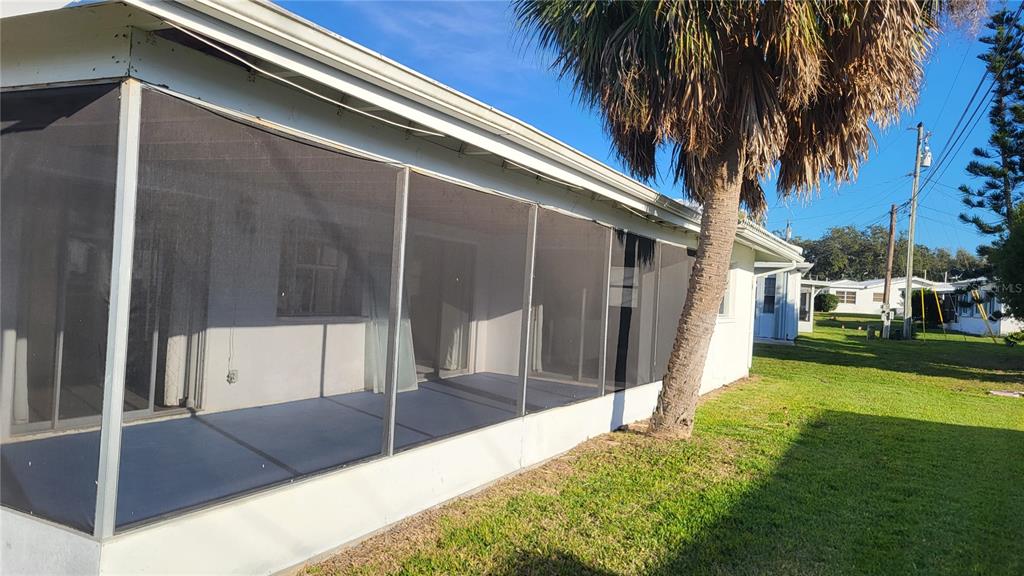 A screened-in porch attached to the side of a house with a palm tree nearby — 14140 88TH AVENUE, SEMINOLE, FL