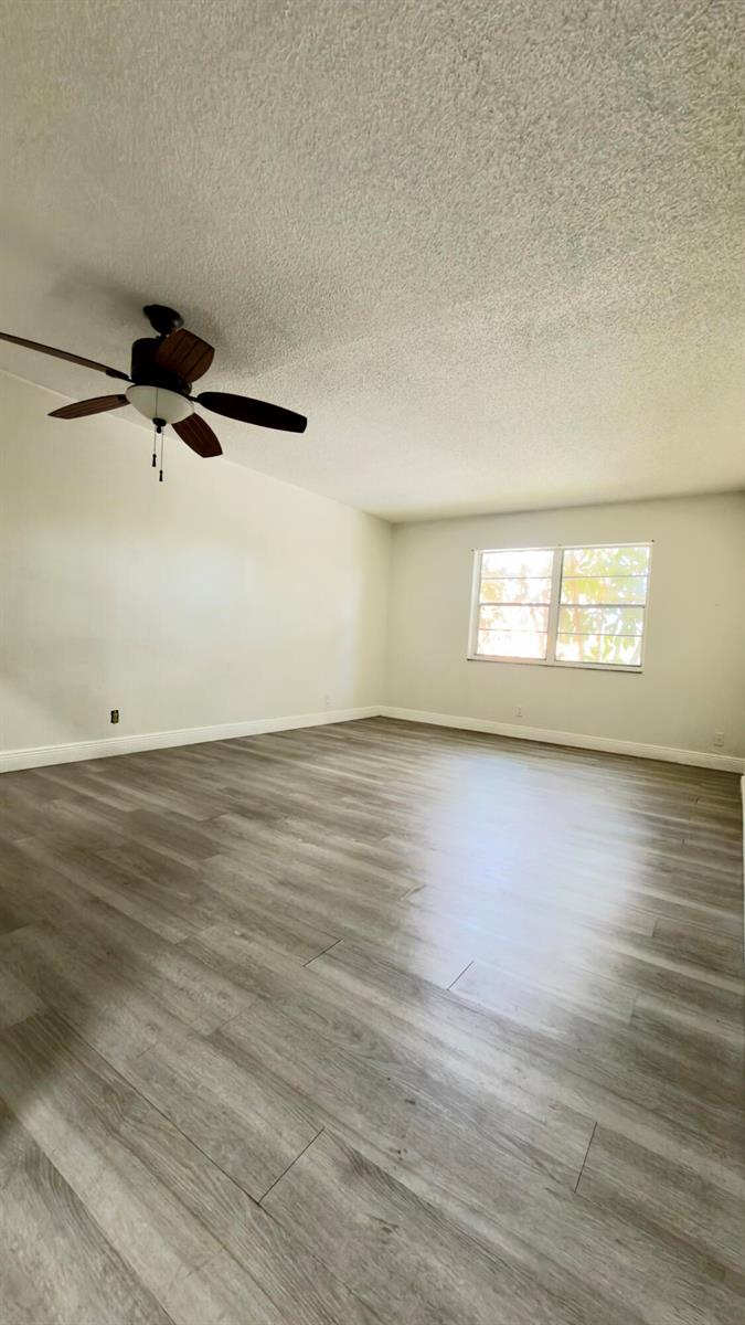 An empty room features light gray wood-look flooring, white walls, and a ceiling fan — 4364 NW 9th # 2a, Deerfield Beach FL 33064, DEERFIELD BEACH, FL