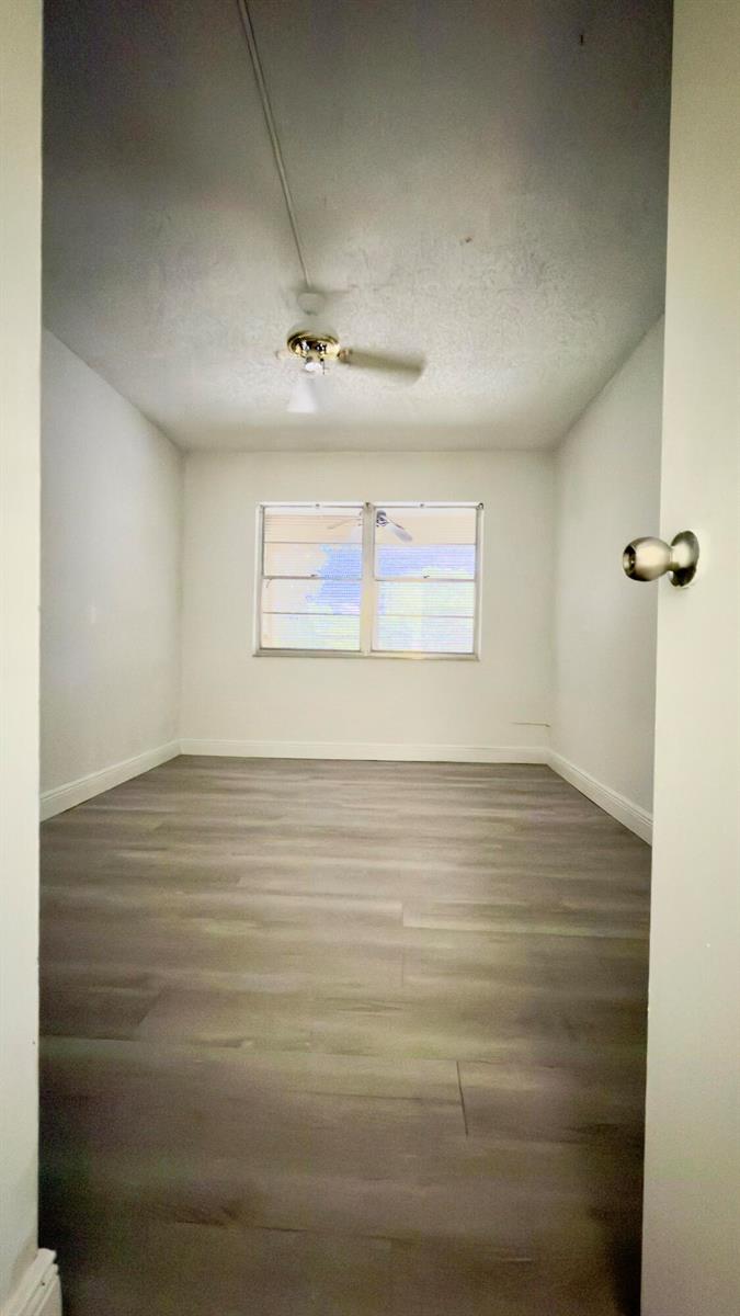 An empty bedroom with white walls, gray wood-look flooring, and a ceiling fan — 4364 NW 9th # 2a, Deerfield Beach FL 33064, DEERFIELD BEACH, FL