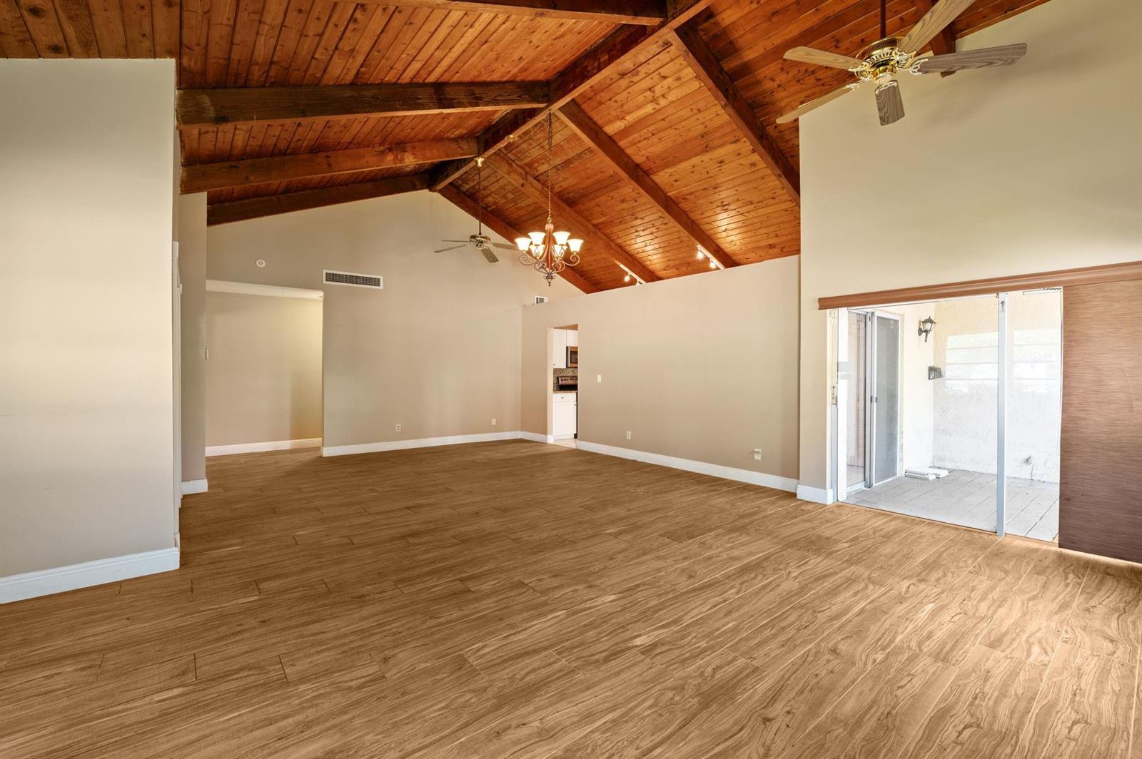 A spacious living room features a vaulted wood-plank ceiling, tile flooring, and sliding glass doors — 2229 Nova Village Drive, Davie FL 33317, DAVIE, FL
