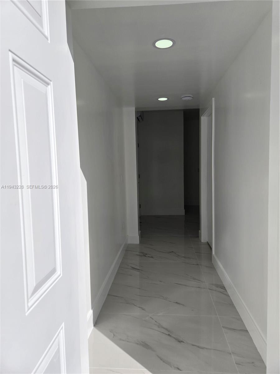 A hallway features white walls, recessed ceiling lights, and light-colored marble-patterned tile flooring — 987 NE 145 # B, North Miami FL 33161, NORTH MIAMI, FL