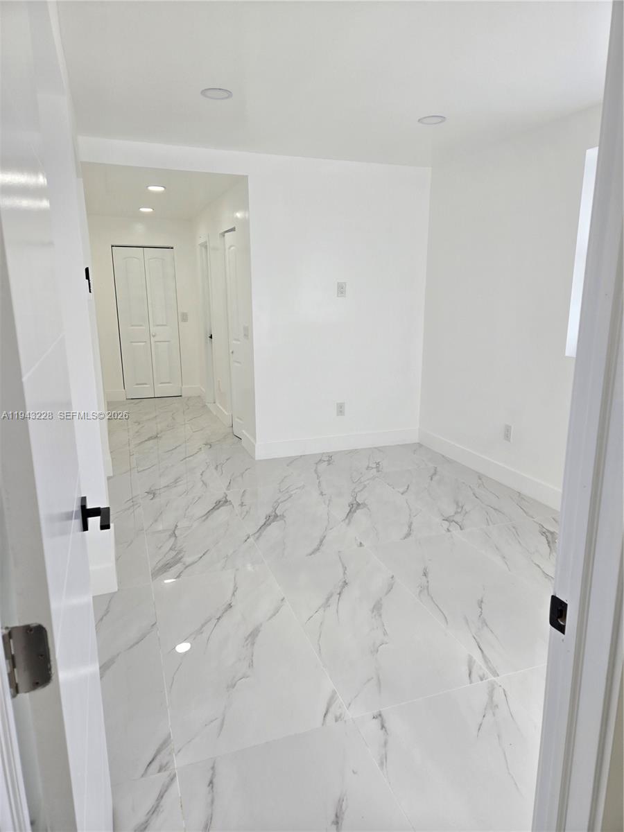 A bright, empty room features white walls, recessed lighting, and white marble-patterned tile flooring — 987 NE 145 # B, North Miami FL 33161, NORTH MIAMI, FL