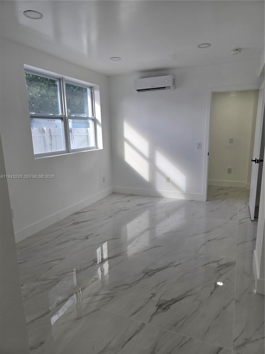 A bright, empty room features white walls, a mini-split air conditioner, and marble-patterned tile flooring — 987 NE 145 # B, North Miami FL 33161, NORTH MIAMI, FL