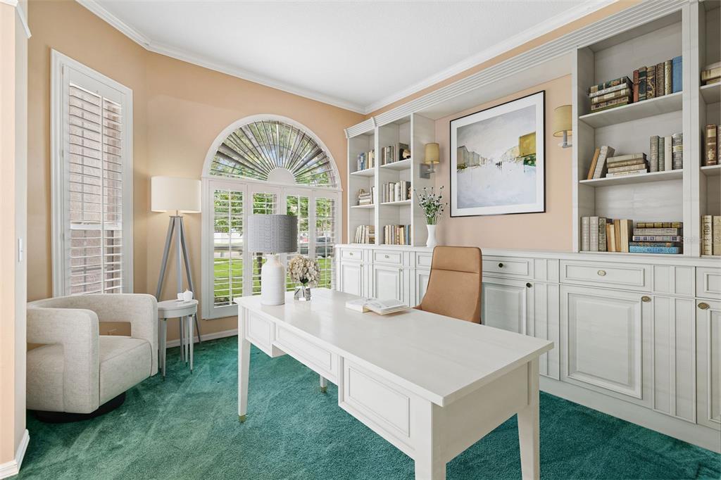 A home office features a white desk, built-in bookshelves, a tan chair, and green carpeting — 12307 BRETON OAK LANE, RIVERVIEW, FL