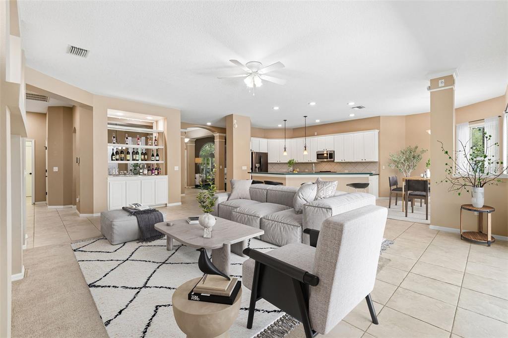 An open-concept living room features a sectional sofa, a built-in bar, and a kitchen — 12307 BRETON OAK LANE, RIVERVIEW, FL