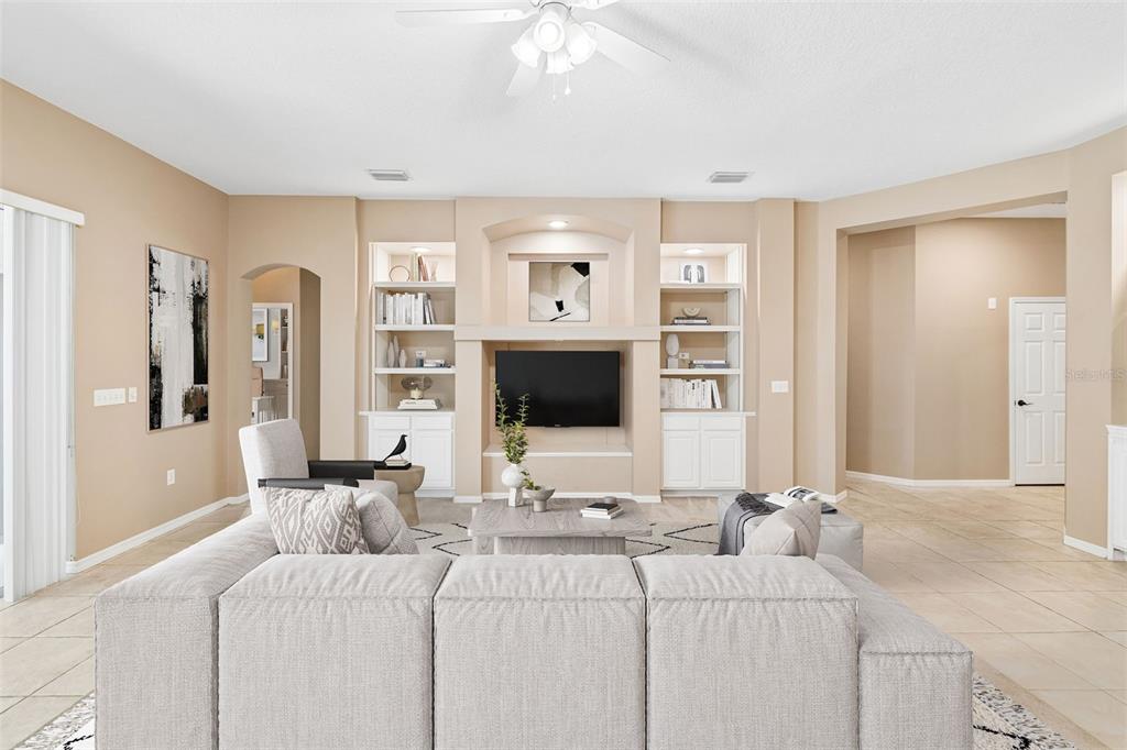 A living room features a large sectional sofa, a television, and built-in shelving units — 12307 BRETON OAK LANE, RIVERVIEW, FL