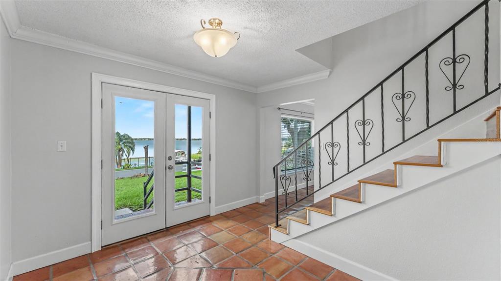 An entryway features terracotta tile flooring, a staircase with wrought iron railings, and glass doors — 1218 LAKE ARIANA BOULEVARD, AUBURNDALE, FL