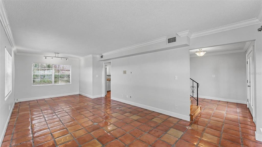 An empty room with terracotta tile flooring, white walls, crown molding, and a staircase — 1218 LAKE ARIANA BOULEVARD, AUBURNDALE, FL