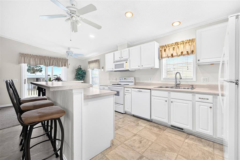 A kitchen with white cabinets, a breakfast bar, and tile flooring — 15550 BURNT STORE ROAD UNIT 237, PUNTA GORDA, FL