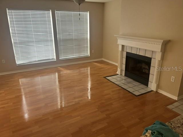 A living room with hardwood floors, two windows with blinds, and a white fireplace — 685 YOUNGSTOWN PARKWAY UNIT 297, ALTAMONTE SPRINGS, FL