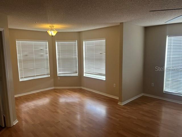 An empty room with light wood flooring, beige walls, and multiple windows with white blinds — 685 YOUNGSTOWN PARKWAY UNIT 297, ALTAMONTE SPRINGS, FL