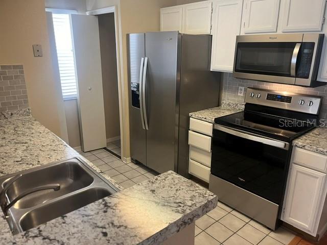 A kitchen features stainless steel appliances, white cabinets, and granite countertops with a double sink — 685 YOUNGSTOWN PARKWAY UNIT 297, ALTAMONTE SPRINGS, FL