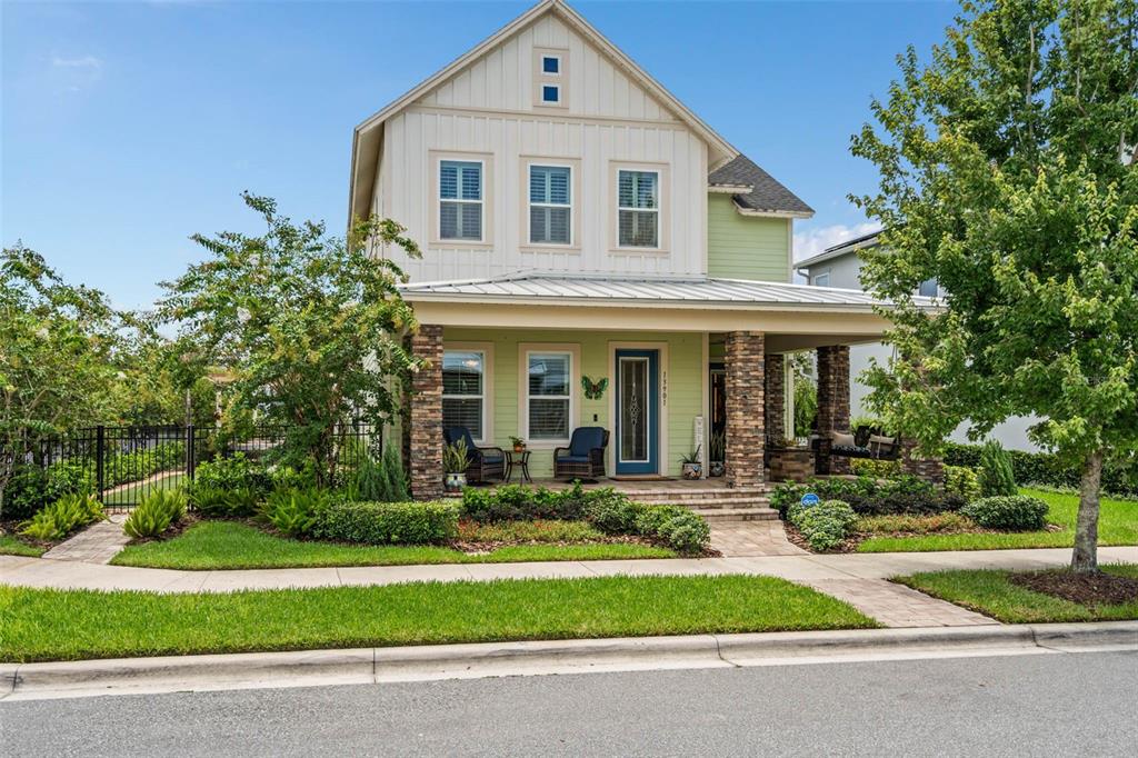 A two-story house with a stone-columned front porch, light green siding, and white vertical trim — 13901 MYERSON AVENUE, ORLANDO, FL