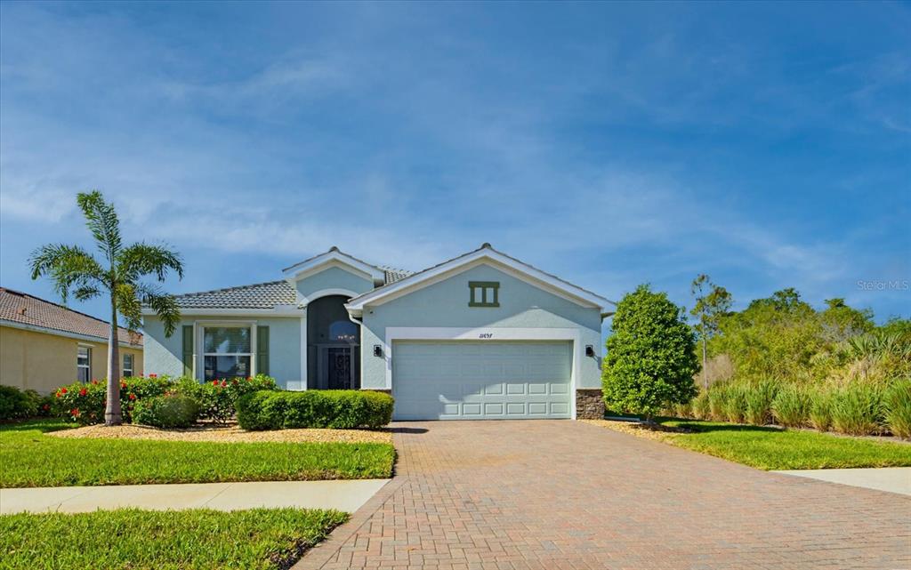 A single-story house with a light-colored stucco exterior, a two-car garage, and a paved driveway — 11697 SPOTTED MARGAY AVENUE, VENICE, FL