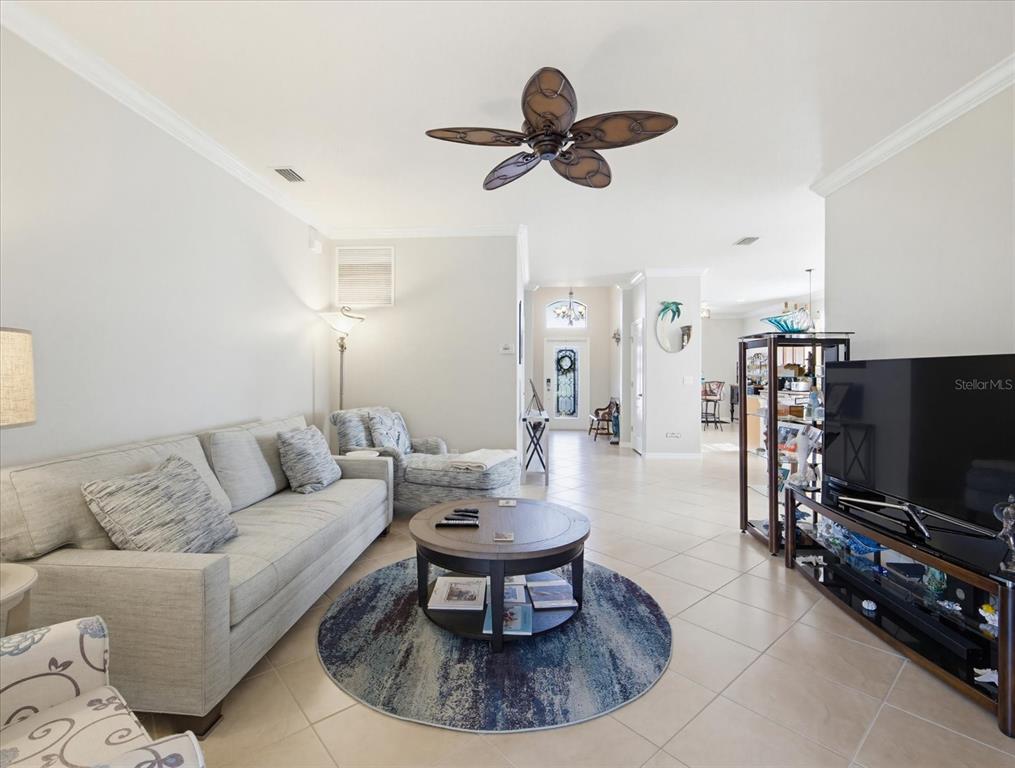 A living room features a light gray sofa, a round coffee table, and tile flooring — 11697 SPOTTED MARGAY AVENUE, VENICE, FL