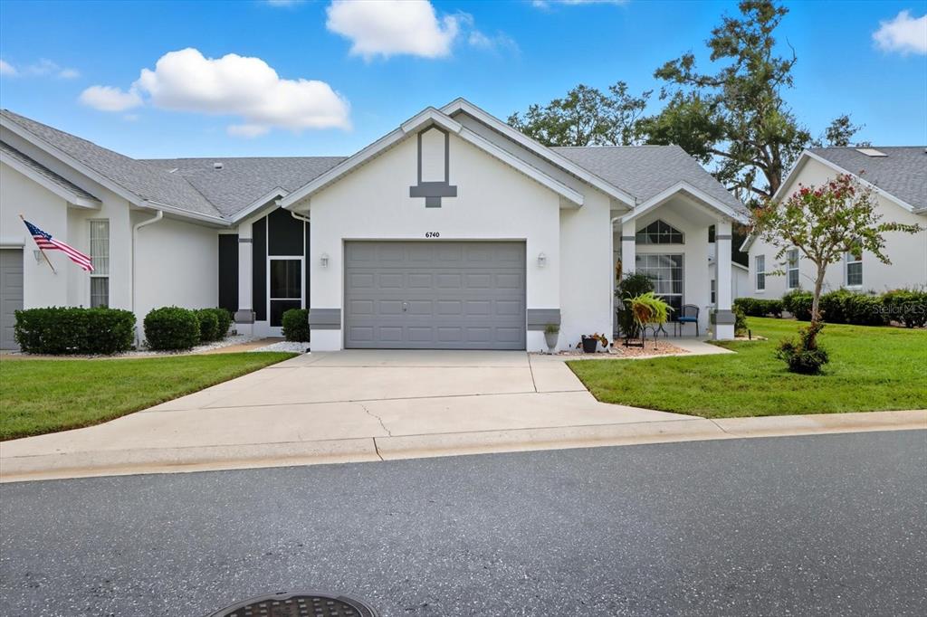 A white single-story house with a gray garage door and a concrete driveway — 6740 E KINGSBURY LANE, INVERNESS, FL