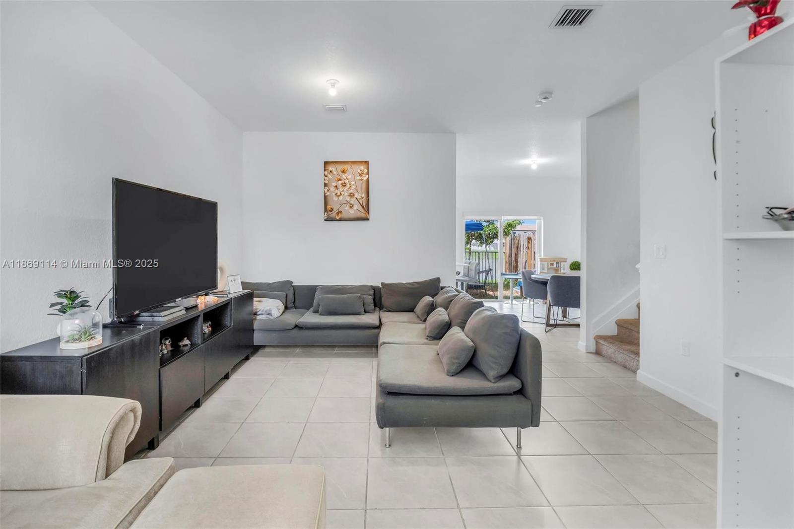 A living room features a large gray sectional sofa, a television console, and tile flooring — 12774 NW 22nd Pl, Miami FL 33167, MIAMI, FL
