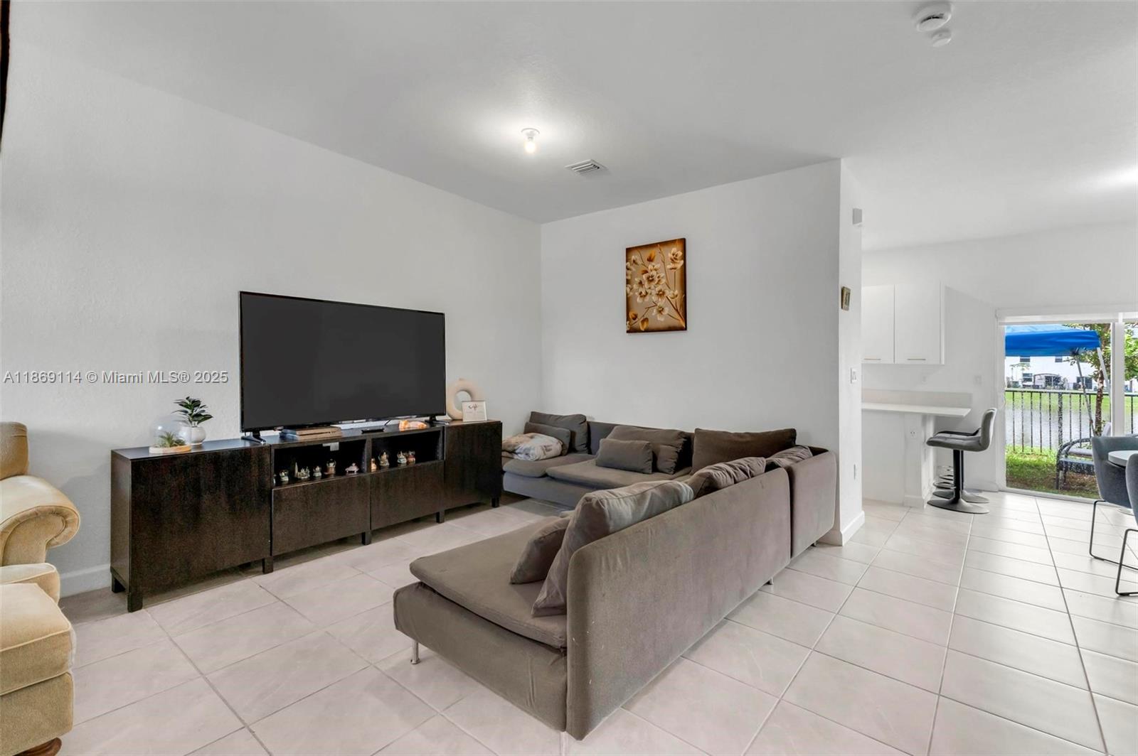 A living room features a large sectional sofa, a television console, and tiled flooring — 12774 NW 22nd Pl, Miami FL 33167, MIAMI, FL