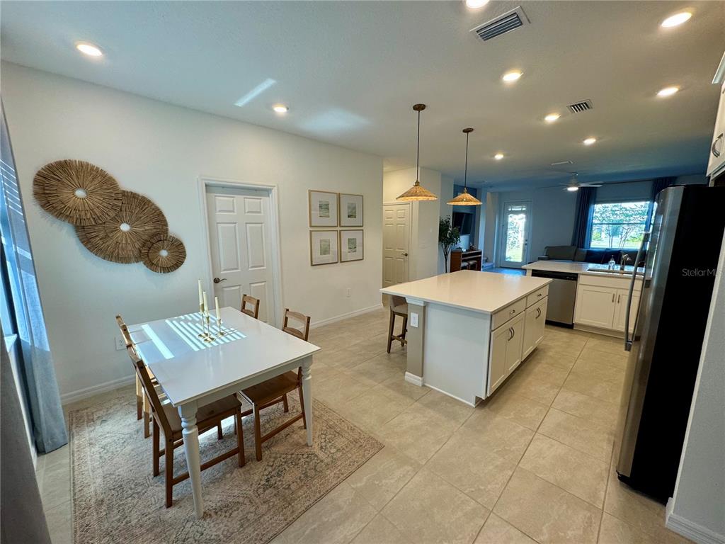 A kitchen with a white island, dining area, and tile flooring in an open floor plan — 1908 SWIVEL LANE, SARASOTA, FL