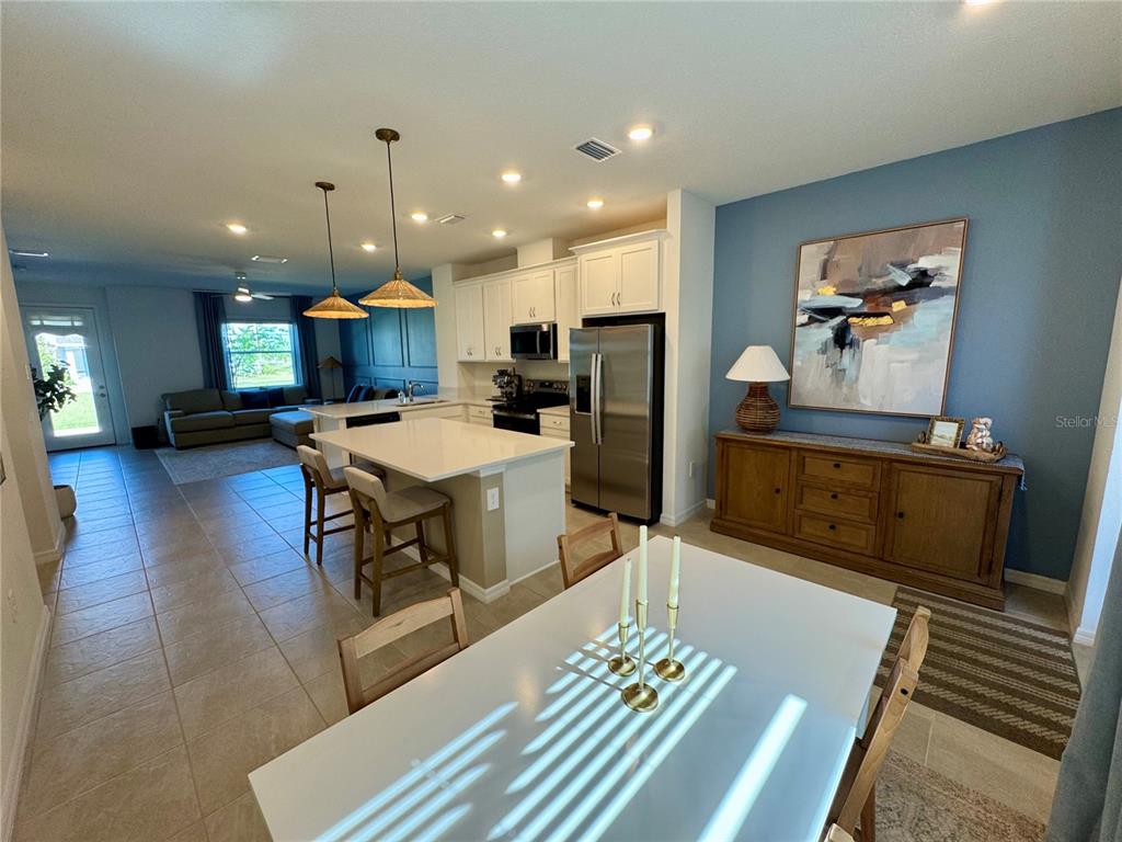 An open-concept kitchen and dining area features white cabinetry, a center island, and blue walls — 1908 SWIVEL LANE, SARASOTA, FL