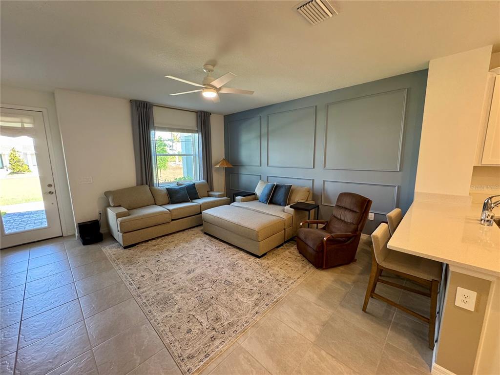 A living room features a blue paneled accent wall, a large sectional, and tile flooring — 1908 SWIVEL LANE, SARASOTA, FL