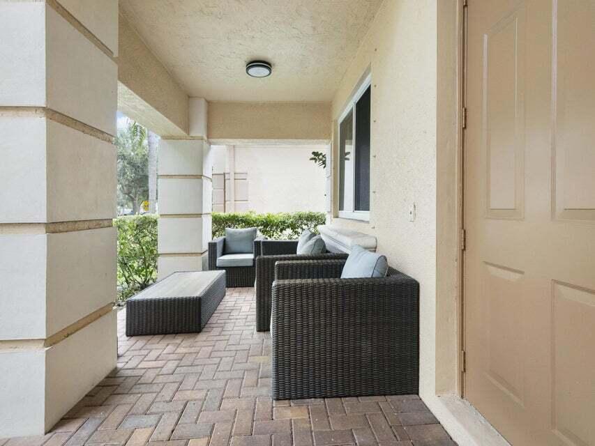A covered patio features brick pavers, wicker furniture, and a beige exterior wall — 846 Gazetta Way, West Palm Beach FL 33413, WEST PALM BEACH, FL