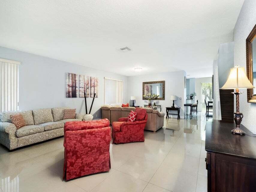 A spacious living room features light tile floors, neutral walls, and a mix of seating — 846 Gazetta Way, West Palm Beach FL 33413, WEST PALM BEACH, FL