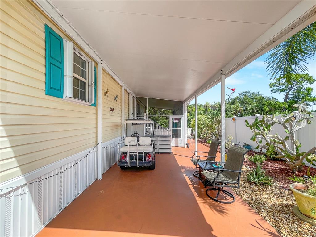 A covered patio features a golf cart, two chairs, and a small table on concrete — 10101 BURNT STORE ROAD UNIT 222, PUNTA GORDA, FL