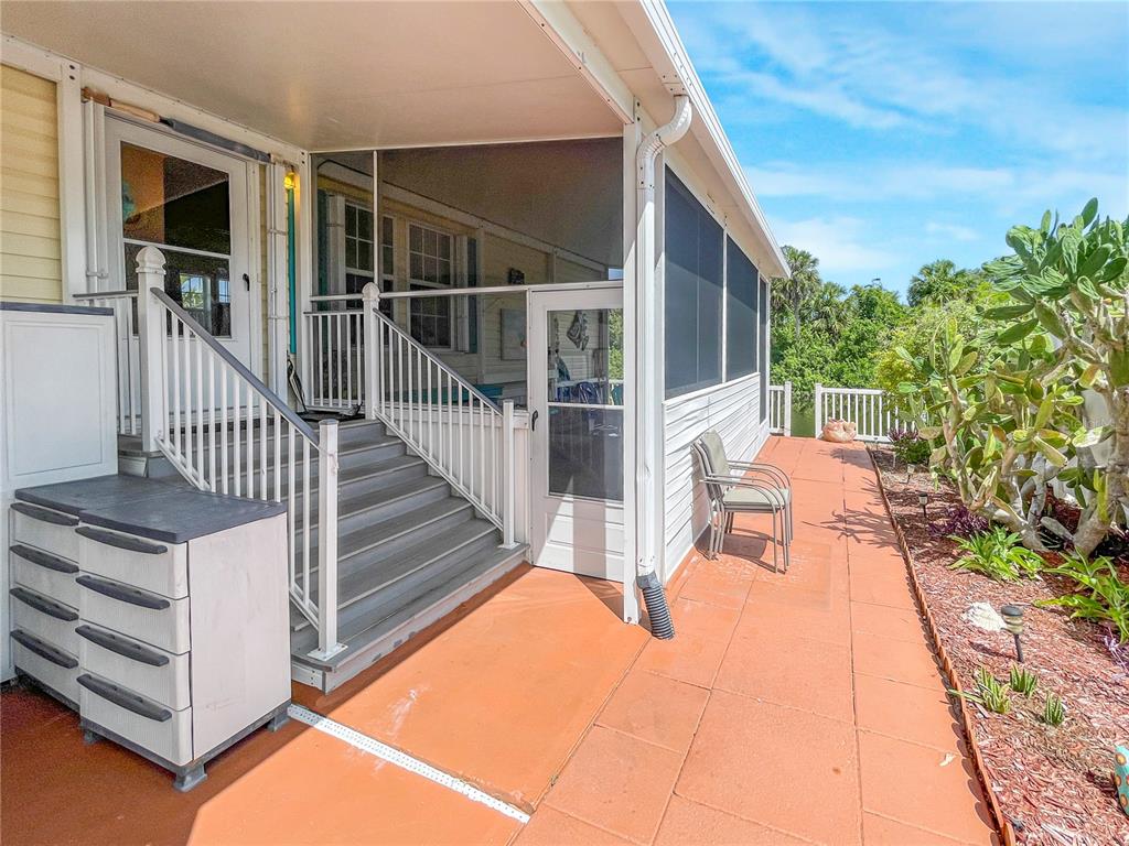 A covered porch with stairs leads to a screened-in patio area with tiled flooring — 10101 BURNT STORE ROAD UNIT 222, PUNTA GORDA, FL