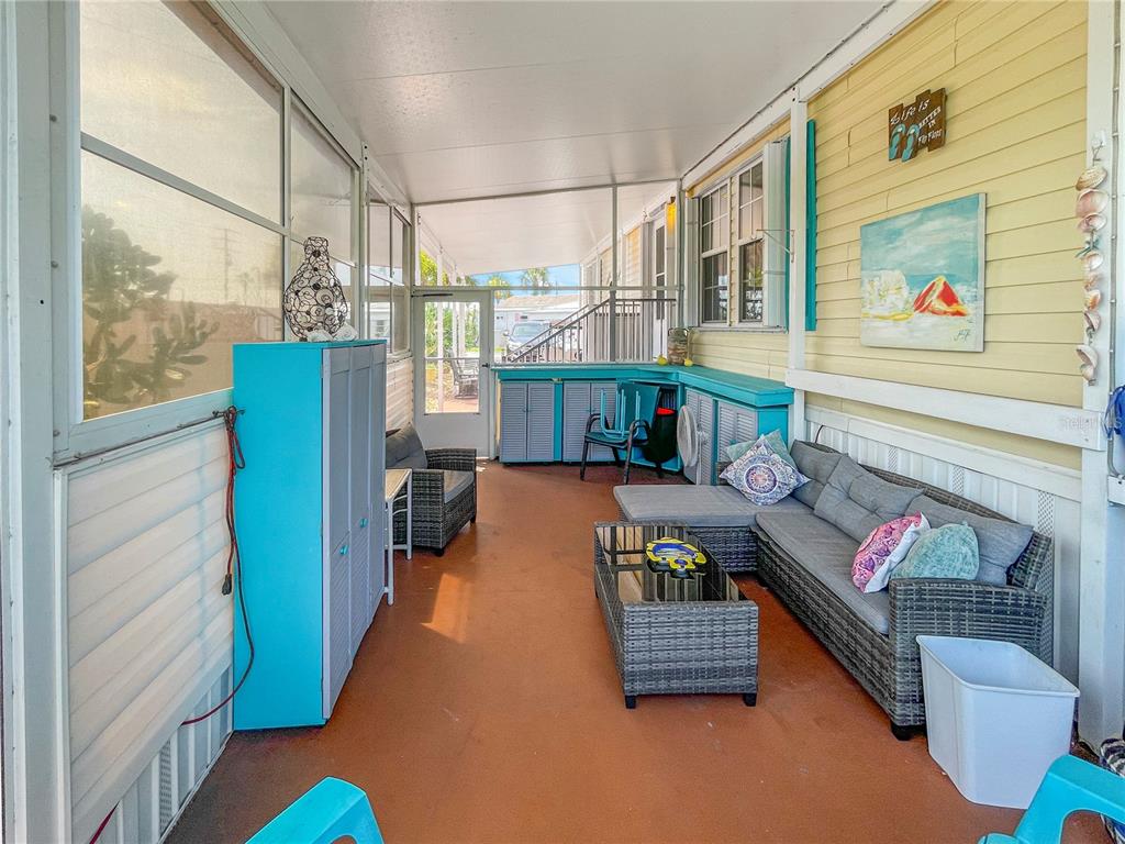 A screened-in porch with a gray sectional sofa, coffee table, and turquoise storage cabinets — 10101 BURNT STORE ROAD UNIT 222, PUNTA GORDA, FL