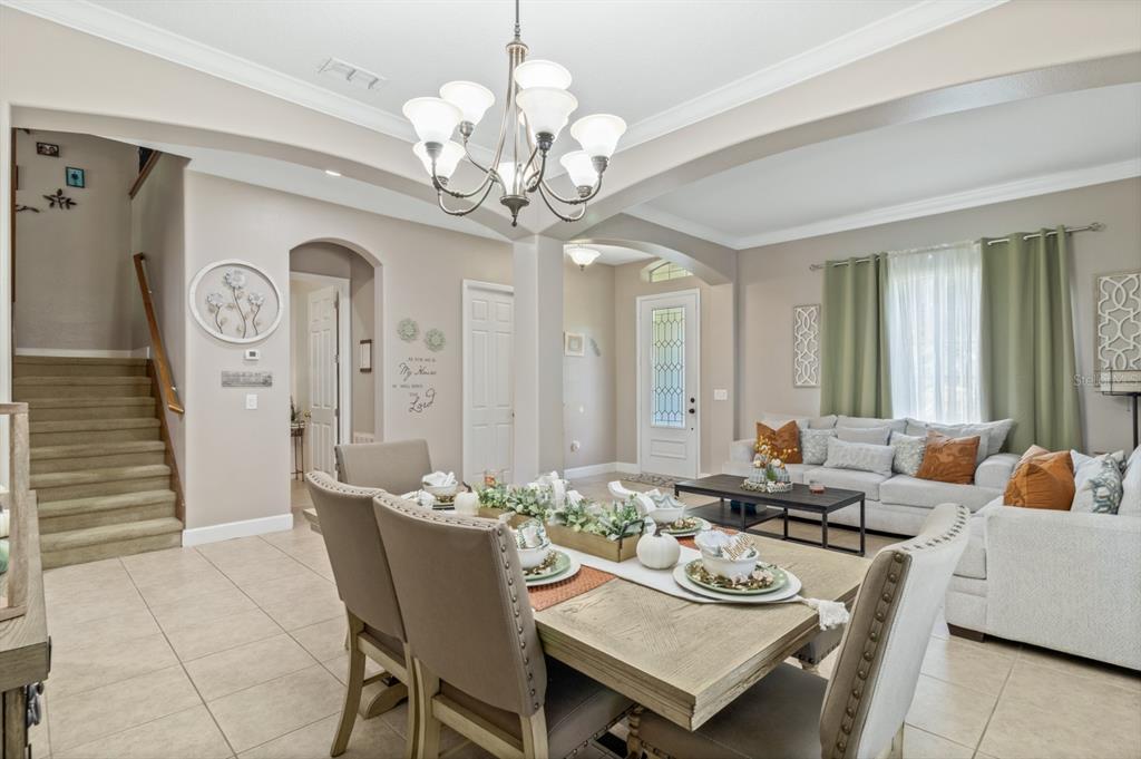 A dining area with a chandelier sits in front of a living room with tile floors — 1705 BRIDGETS COURT, KISSIMMEE, FL