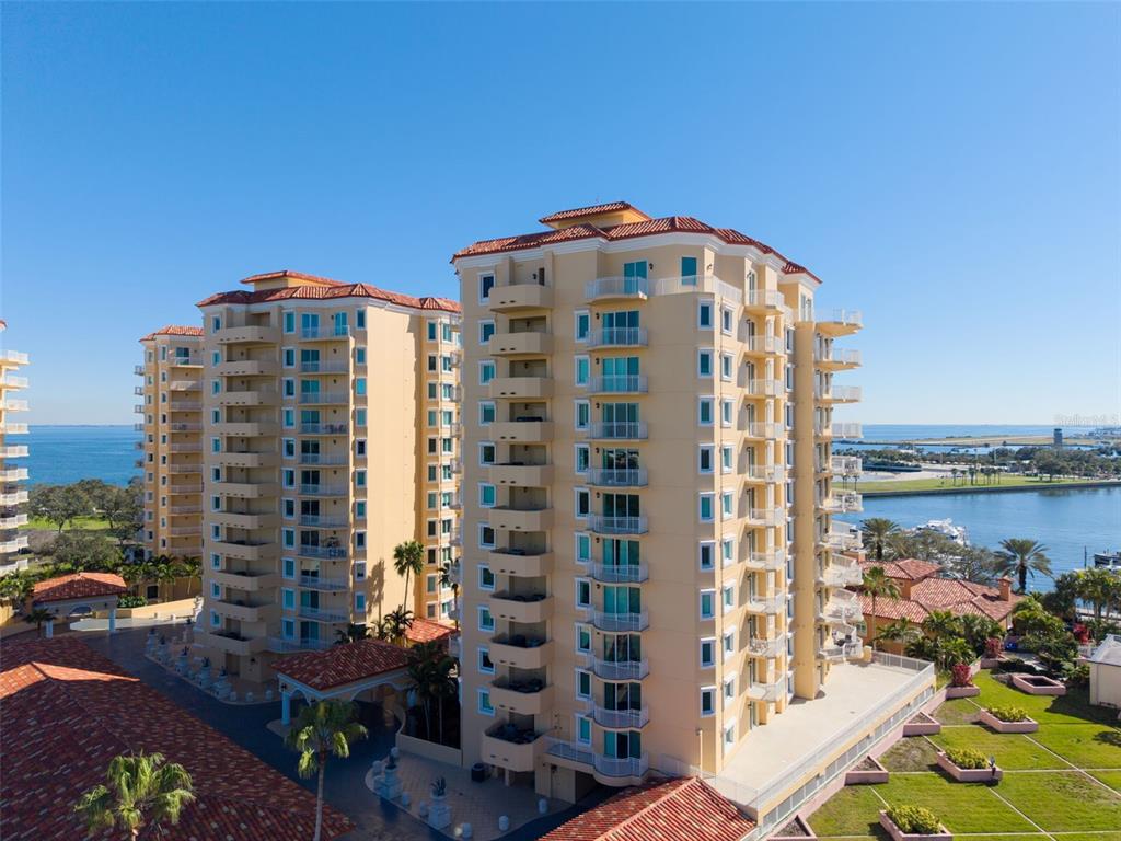 Two tall, tan residential buildings with red tile roofs overlook a bay and marina — 555 5TH AVENUE NE UNIT 1122, ST PETERSBURG, FL