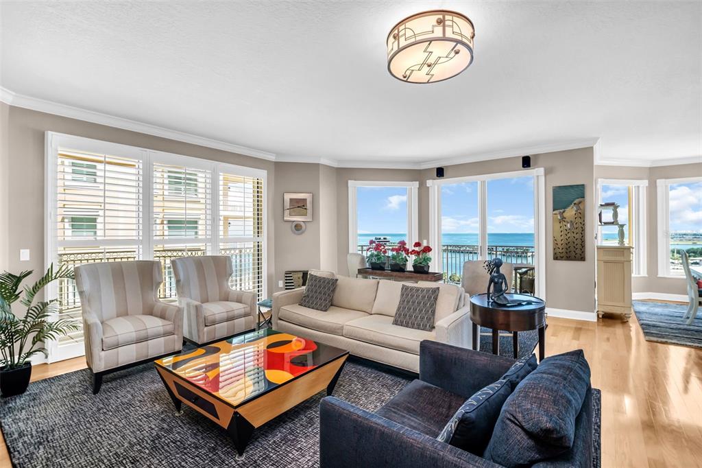 A living room features a colorful coffee table, beige sofa, armchairs, and a view of water — 555 5TH AVENUE NE UNIT 1122, ST PETERSBURG, FL