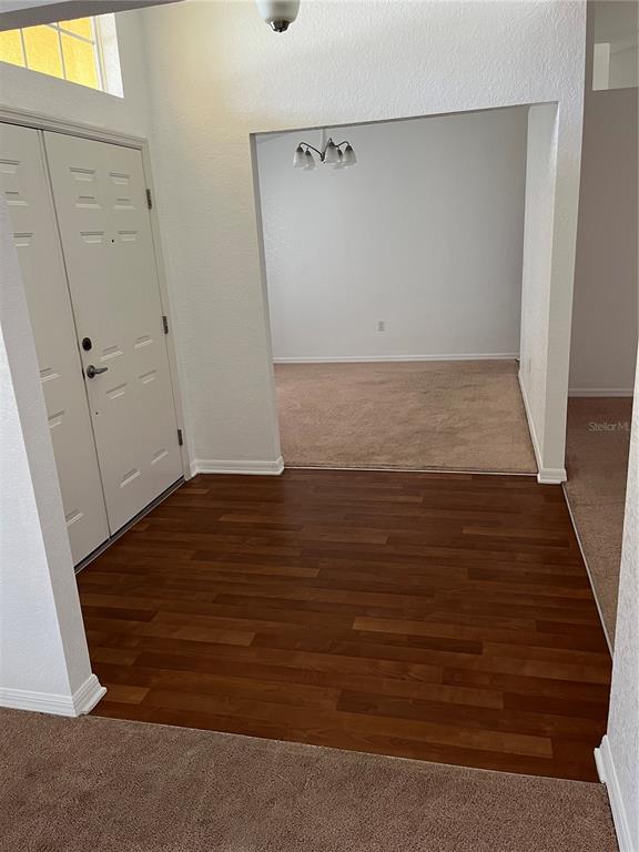An entryway with wood-look flooring leads to a carpeted dining area with a light fixture — 3362 WINCHESTER ESTATES CIRCLE, LAKELAND, FL