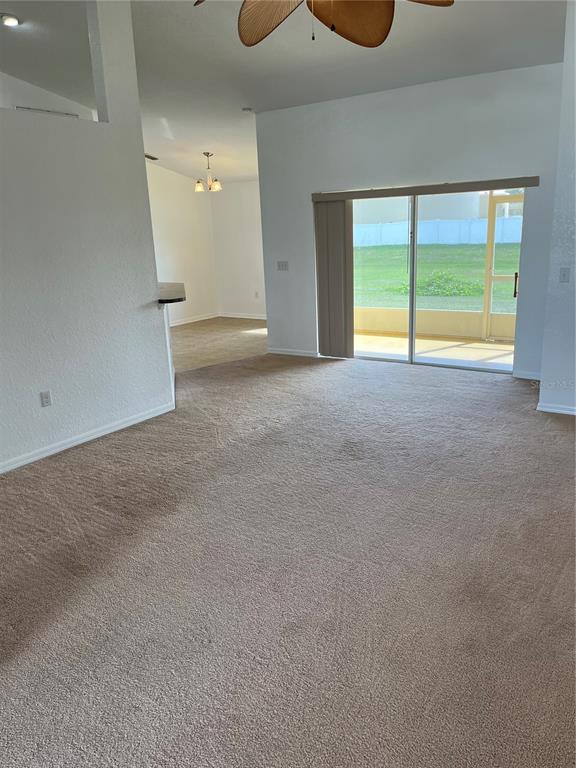 A living room with beige carpeting, a ceiling fan, and sliding glass doors to a patio — 3362 WINCHESTER ESTATES CIRCLE, LAKELAND, FL