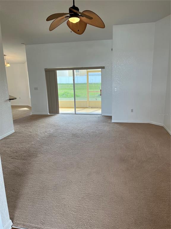 A carpeted living room features a ceiling fan and sliding glass doors leading to a patio — 3362 WINCHESTER ESTATES CIRCLE, LAKELAND, FL