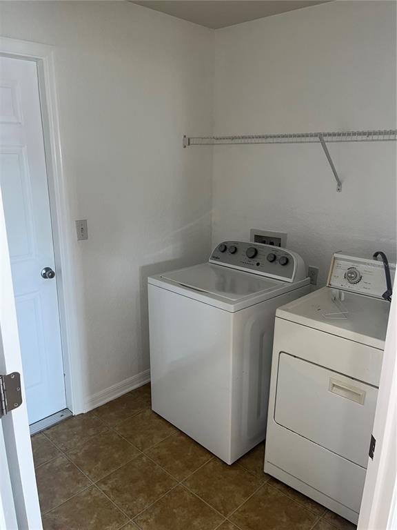 A laundry room features a white washer and dryer, tile flooring, and a wire shelf — 3362 WINCHESTER ESTATES CIRCLE, LAKELAND, FL