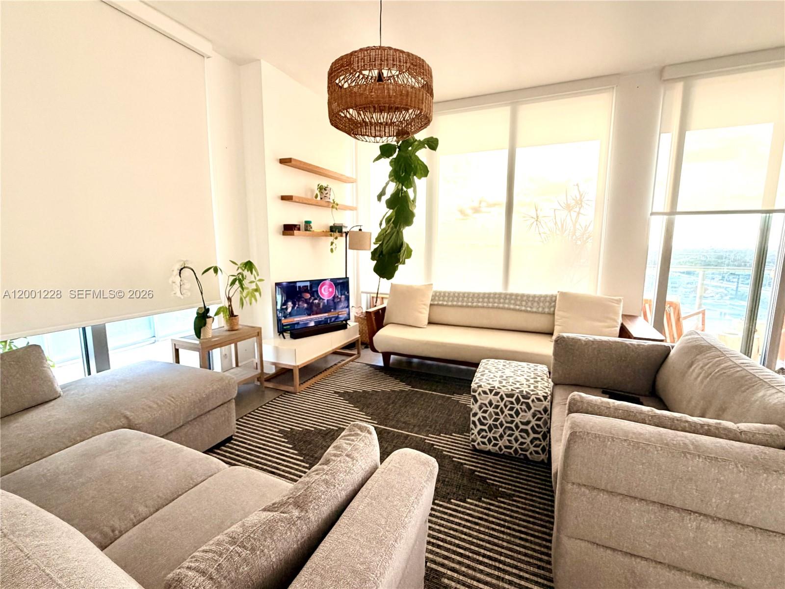A living room features a sectional sofa, a patterned rug, and large floor-to-ceiling windows — 3470 E Coast Ave # H1610, Miami FL 33137, MIAMI, FL