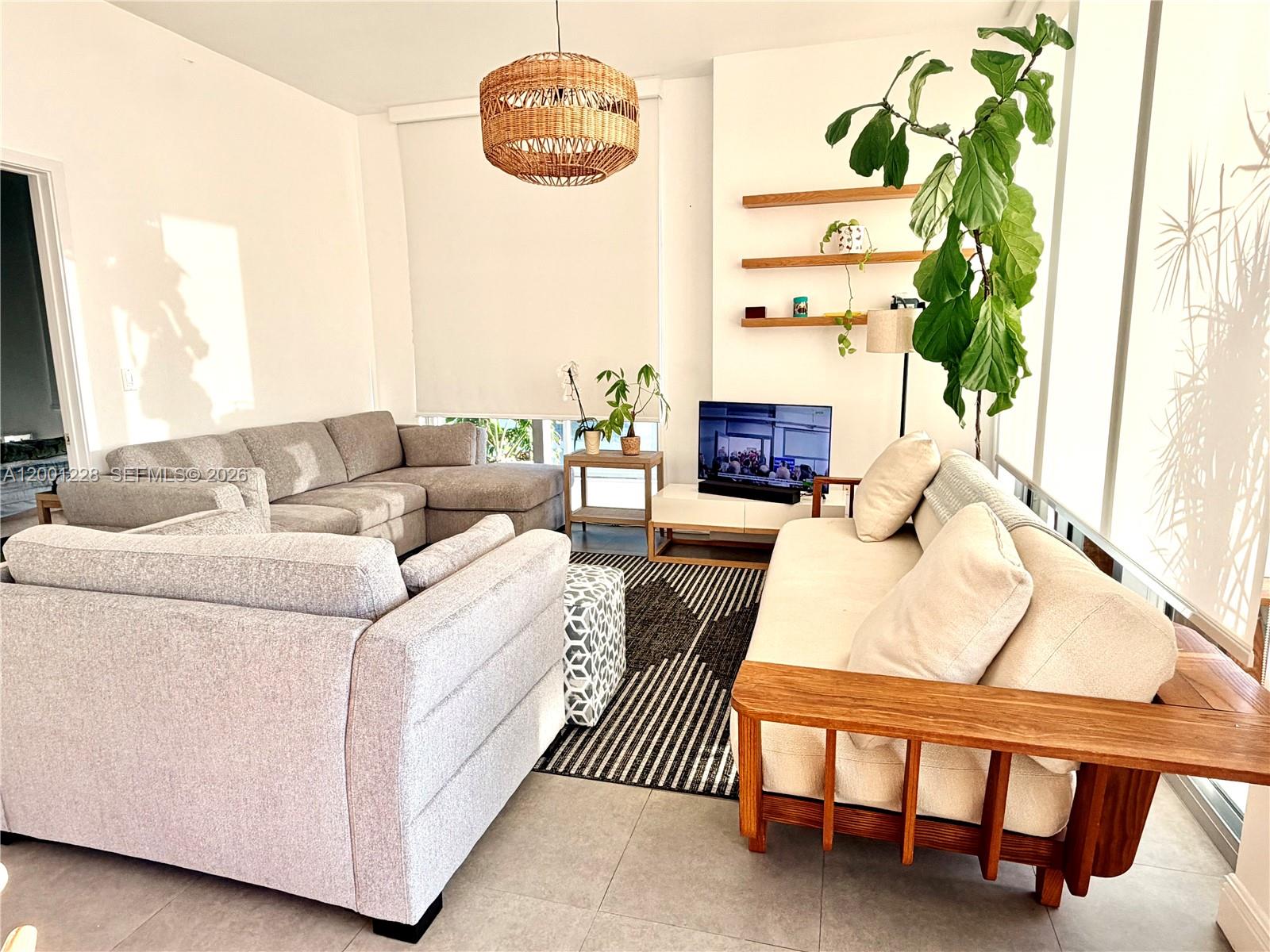 A living room features a sectional sofa, a wooden-framed couch, and a woven pendant light — 3470 E Coast Ave # H1610, Miami FL 33137, MIAMI, FL